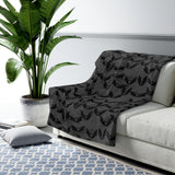 demonstration image of the grey with black bat print blanket, draped over sofa