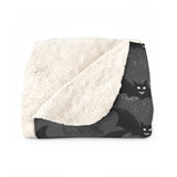folder blanket showing the white sofa side of blanket and al little bit of the dark grey with black bat print top side