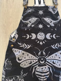 Black celestial witchy style shortalls dungaree overalls with gray moth and moon phase pattern on a white background by Alternawear clothing front close up