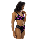 Model wearing a recycled material bikini which is black with a pink alien slug print from a side angle