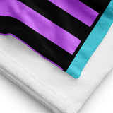 Close up of a Purple and black striped towel with teal detail folded up with th white Terry fabric backing.