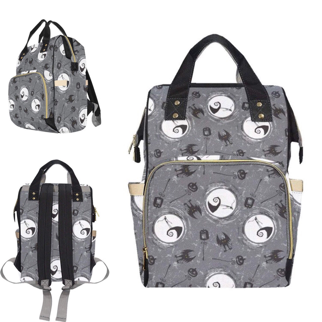 A gray baby changing bag featuring a pattern with skulls and bows, with an emphasis on a character resembling Jack Skellington from 'The Nightmare Before Christmas'. The bag has multiple compartments and is shown from different angles, by Alternawear