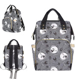 A gray baby changing bag featuring a pattern with skulls and bows, with an emphasis on a character resembling Jack Skellington from 'The Nightmare Before Christmas'. The bag has multiple compartments and is shown from different angles, by Alternawear
