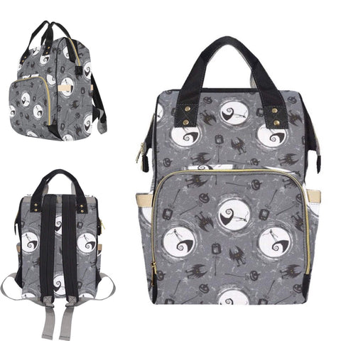 A gray baby changing bag featuring a pattern with skulls and bows, with an emphasis on a character resembling Jack Skellington from 'The Nightmare Before Christmas'. The bag has multiple compartments and is shown from different angles, by Alternawear
