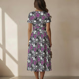 Woman wearing a dress with a skull and spiderweb ghost pattern in a sunlit room.