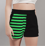 front shot of model wearing shorts that are black with a right handmade mismatch print of green stripes