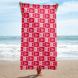 checkered cherry and heart print rockabilly style towel being held up next to the sea