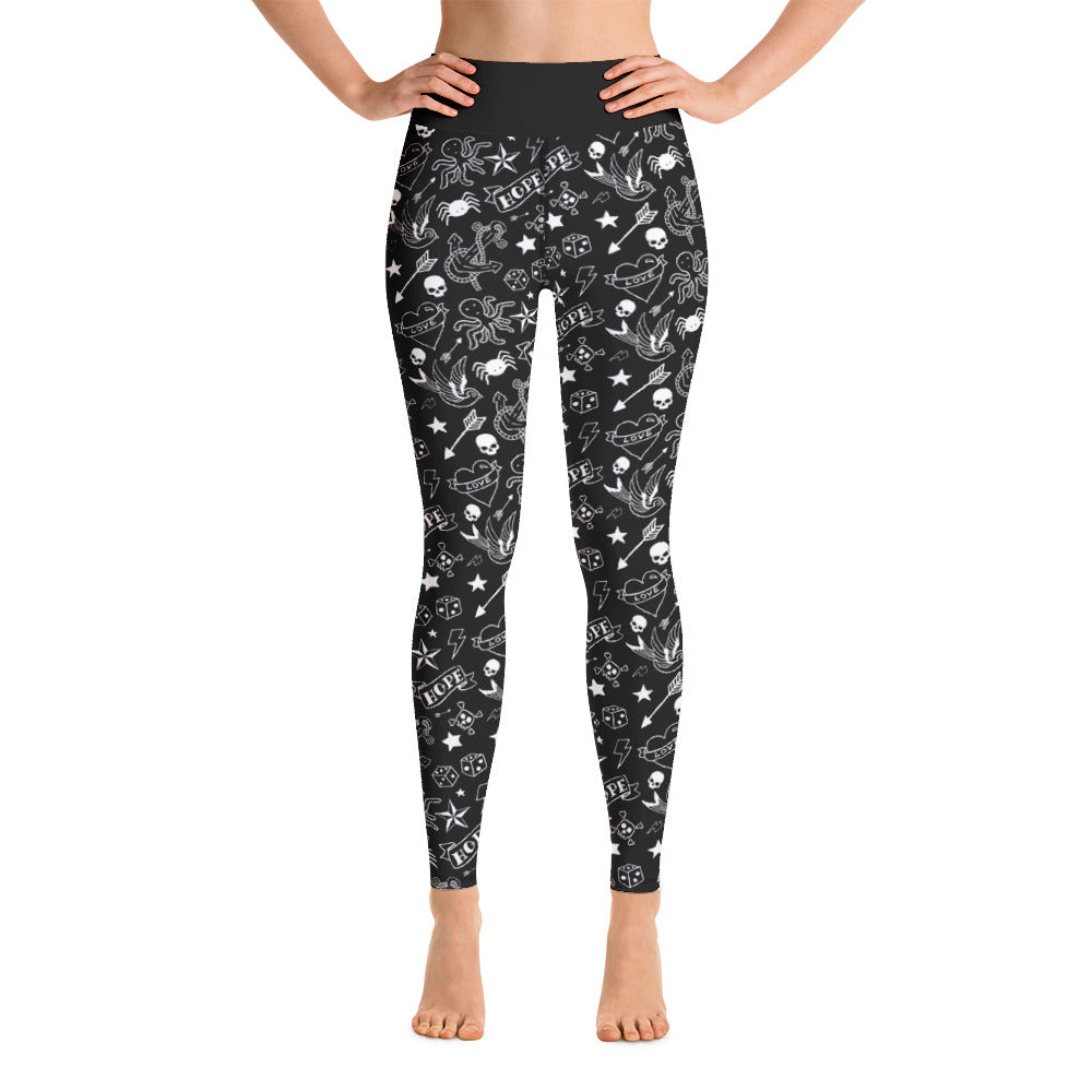 front on shot of model wearing black gym leggings with a classic white tattoo print including skulls, hearts, dice, anchors and swallows
